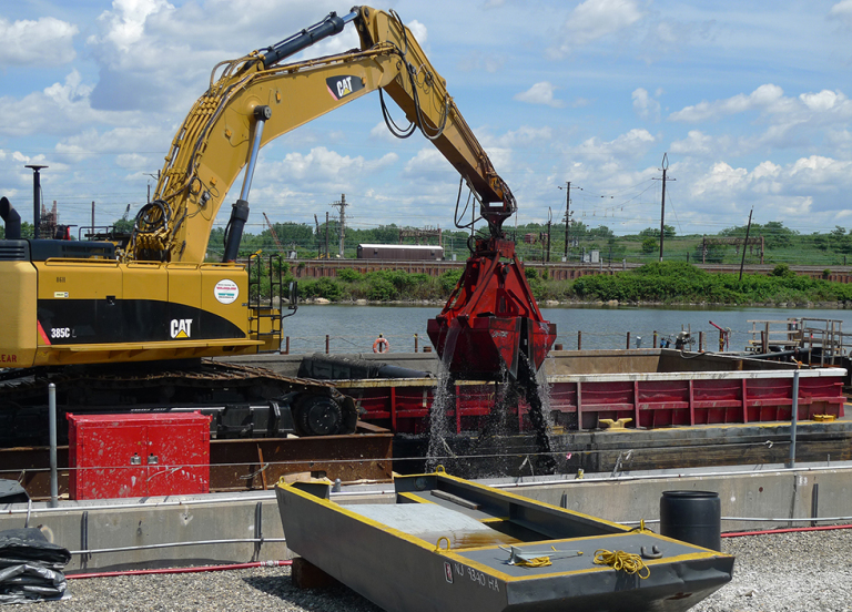 A mechanical dredge removing sediment near a body of water.
