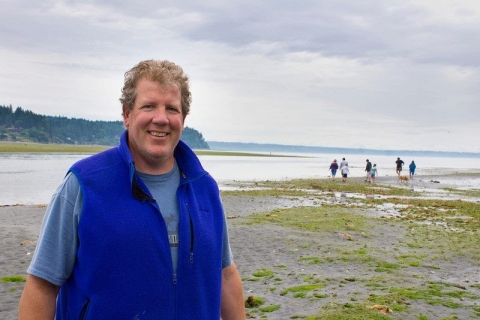 A man standing in an area of tidal flats.