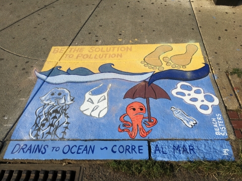A sidewalk painting of trash in the ocean. 