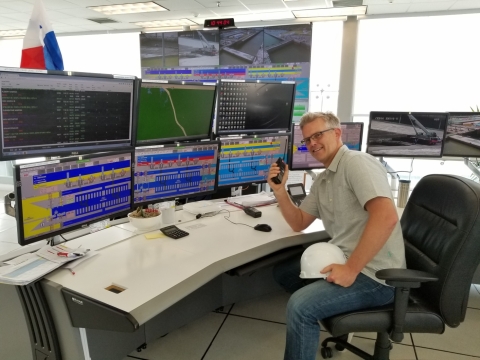 A man at a desk with multiple computer screens. 