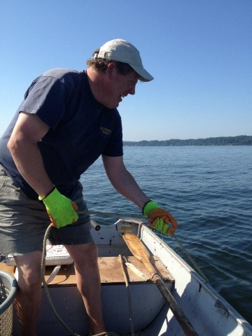 A man on a boat pulling a rope from the water.