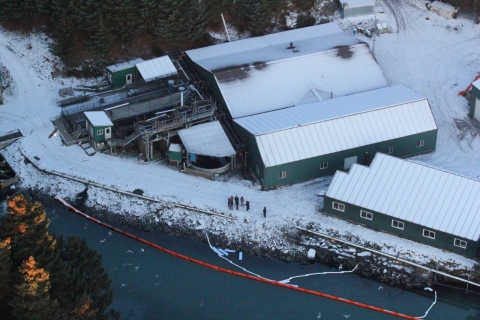 An aerial view of pollution boom along a shoreline with buildings.