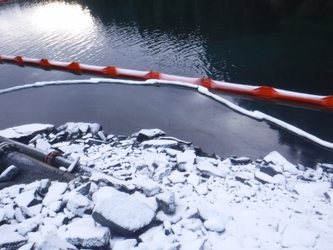 Pollution boom and sorbent along a snowy shoreline.