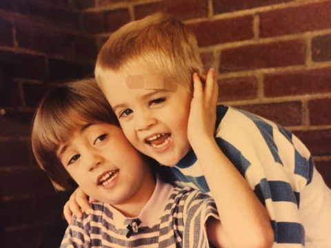 A young girl loving holds the face of a young boy in a hug.