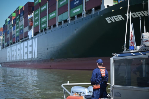 A small boat with a containership in the background. 