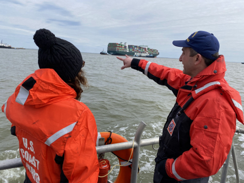 Two people look out at a containership.