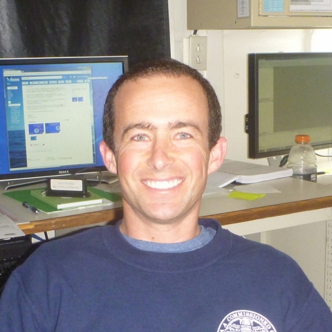 Man smiling in an office, in front of a computer monitor.