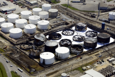 An aerial view of a tank farm with several tanks burned, damaged, and collapsed.