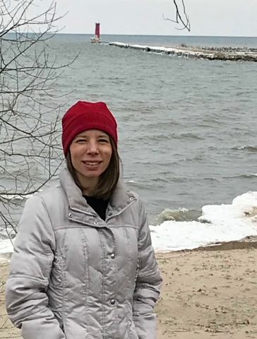 A woman on a beach with a lighthouse in the background. 