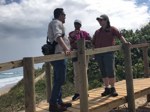 Three people standing on a bridge. 