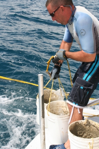 A man on a boat hoisting up two buckets.