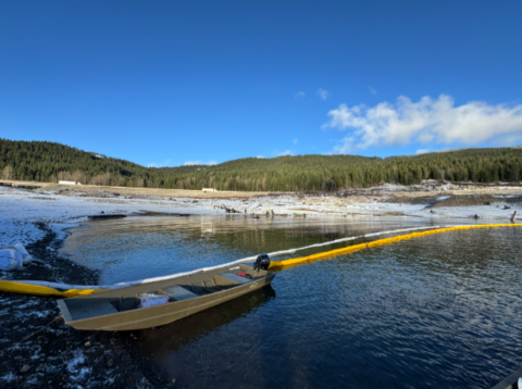 A vessel anchored on the lake shoreline next to a spill boom.