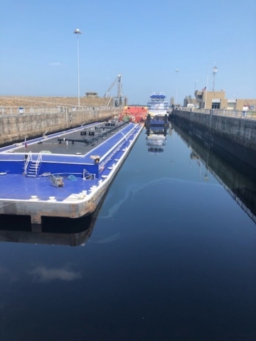 A barge in a lock filled with dark water.