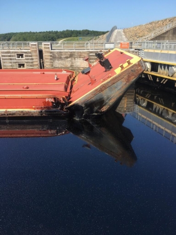 A puncture in the side of a barge with oil visible around the hole. 