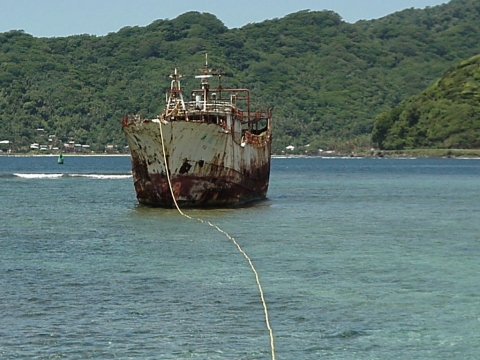 A grounded derelict vessel with a pumping line coming from it.