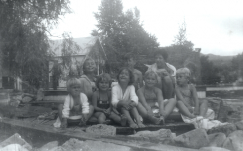 A group of children on rocks next to a lake.