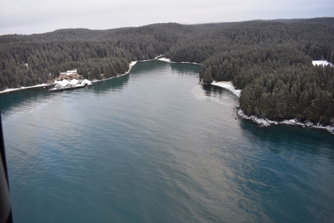 A view of a water with a winter landscape in the background. 
