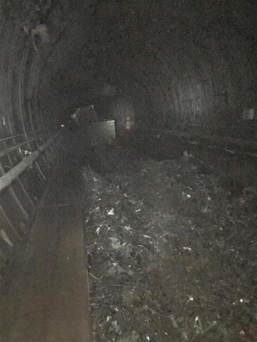 A dark image of the inside of a tunnel with liquid on the ground. 