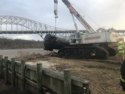 A crane pulling a shipping container out of the water. 