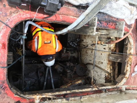 A person working on an oiled vessel compartment. 