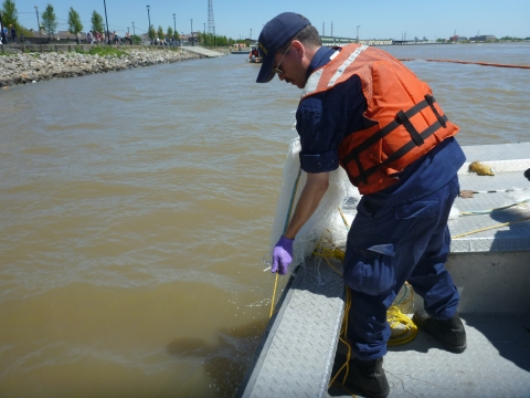 A man in a life preserver on a boat pulls a snare up from the water.