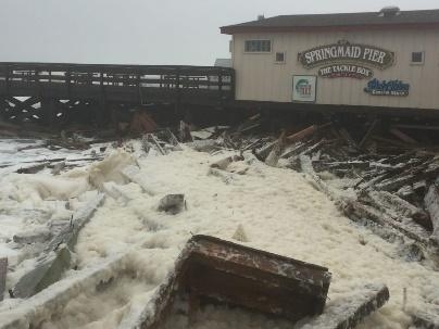 A damaged dock and building next to water.