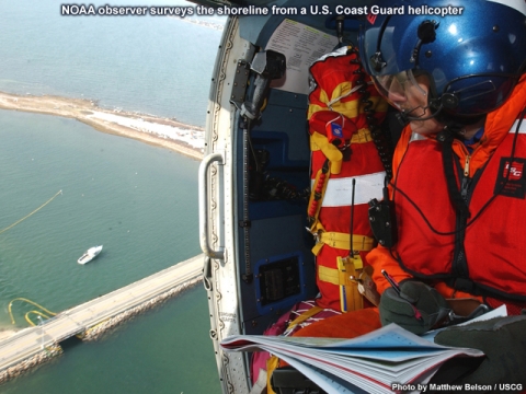 A man on a helicopter looking down at a body of water.