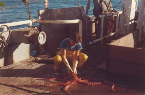 A woman holding an octopus on a boat.
