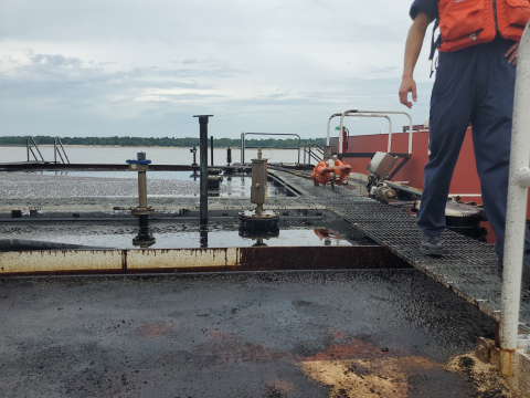 Person standing on deck of a barge.