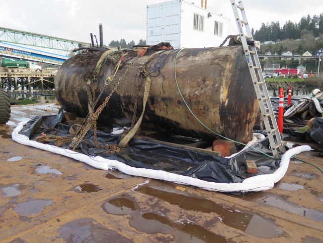 Oiled tank on dock surrounded by boom. 