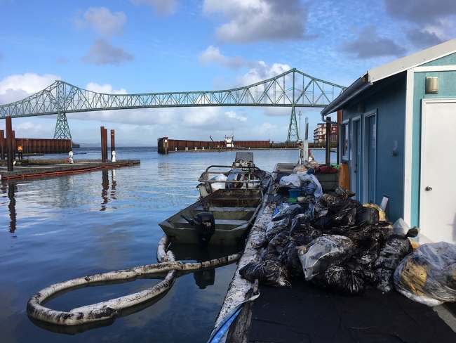 Boat next to dock with oiled bags.
