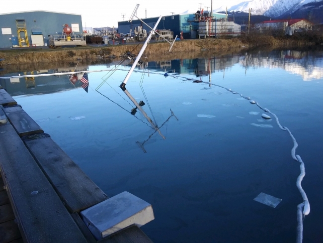 A sunken vessel at a dock with sorbent around it. 