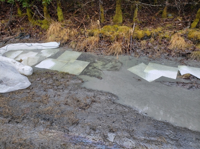 Visible oil in a small area of water with pollution sorbent around it.
