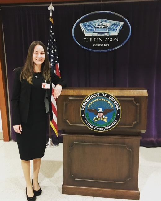 A woman standing next to a podium with a sign reading "The Pentagon" in the background. 