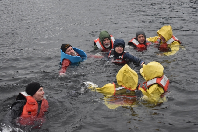A group of people in life preserves in water.
