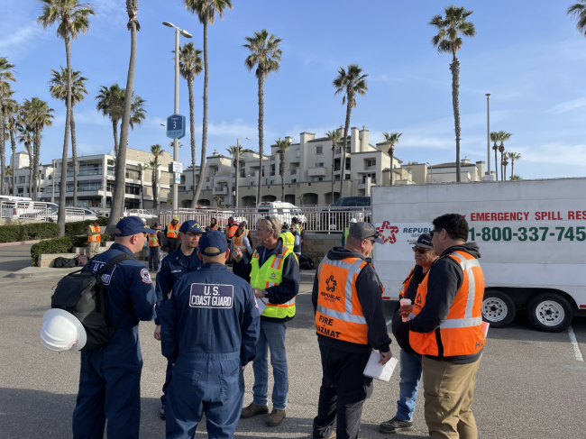 A group of responders gather for a briefing in a local parking lot
