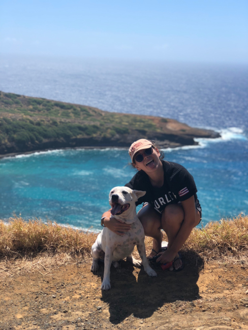 A person and a dog pose for a photo with a water landscape in the background.