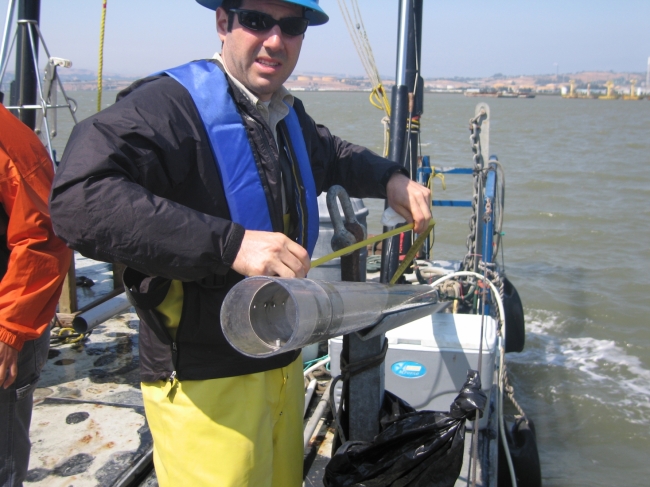 A man on a boat holding a piece of tubing. 