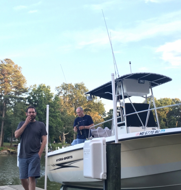 A man on a dock standing next to a man on a boat. 