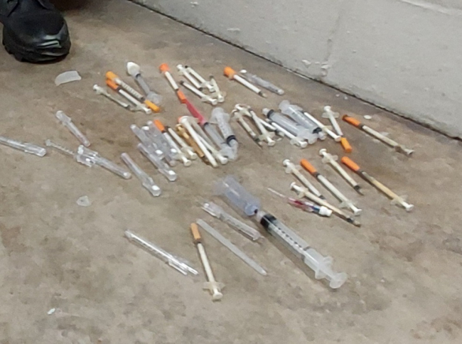 Medical waste removed from beach sits in a pile on a cement floor.