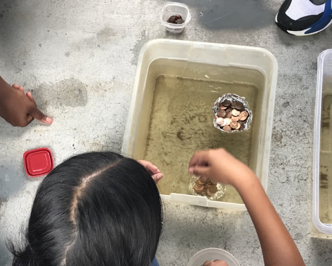 Student with aluminum foil boat full of pennies.