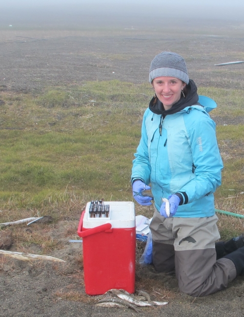 A woman next to a portable cooler. 