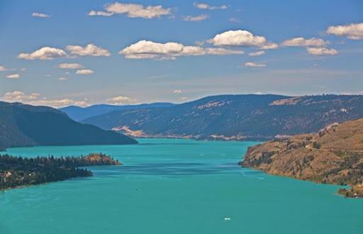 Colorful lake with hills in background.