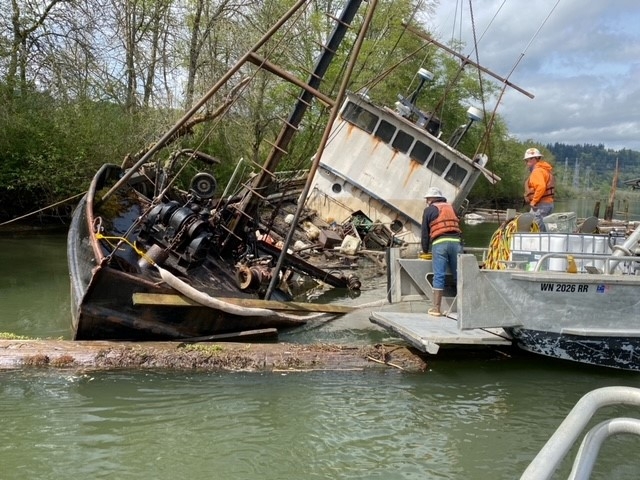 Responders boarding a vessel leaning on its side.