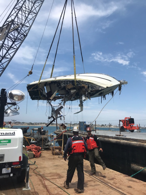 A damaged boat being raised by a crane.