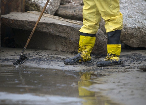 A person cleaning up oil on a beach.