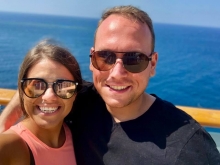 Two people posing for a photo with a body of water in the background.