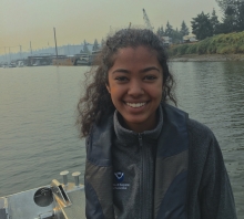 A girl on a boat with an industrial shoreline in the background. 