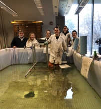A group of people pose in and behind a small pool of water.