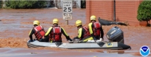 A boat with several people in response gear floating through a flooded street.